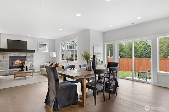 dining area featuring a fireplace, wood finished floors, and plenty of natural light
