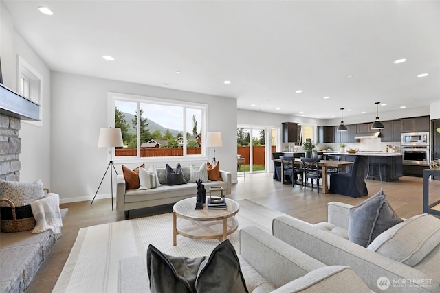 living room featuring light wood finished floors, baseboards, a fireplace, and recessed lighting