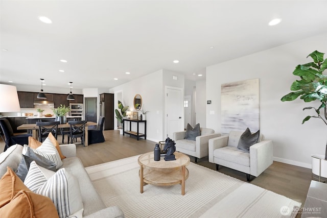 living room featuring baseboards, recessed lighting, and light wood finished floors