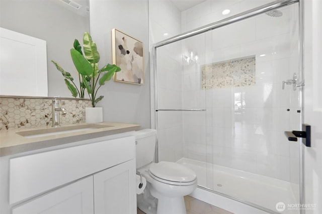 bathroom featuring visible vents, toilet, vanity, tasteful backsplash, and a stall shower