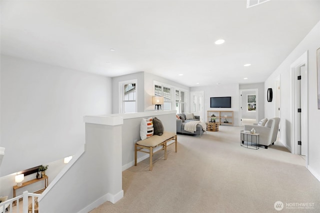 living area featuring an upstairs landing, baseboards, light colored carpet, and recessed lighting