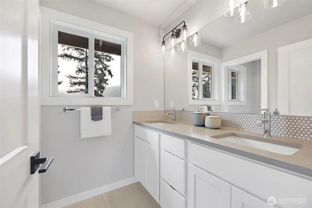 full bath featuring double vanity, a sink, tasteful backsplash, and baseboards