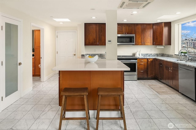 3022 SW Bradford St Unit 401, Seattle, WA 98126 - kitchen with light countertops, a center island, stainless steel appliances, marble finish floor, and a sink