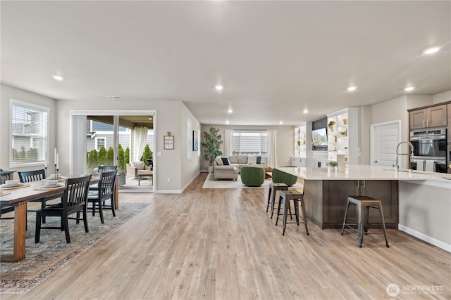 22819 SE Fir St, Black Diamond, WA 98010 - kitchen with light wood-style floors, double oven, a kitchen bar, light countertops, and open floor plan