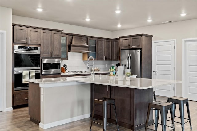 22819 SE Fir St, Black Diamond, WA 98010 - kitchen featuring dark brown cabinetry, visible vents, appliances with stainless steel finishes, custom range hood, and backsplash