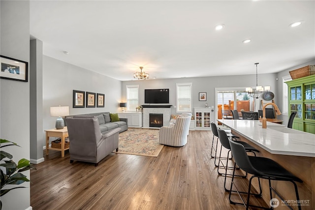 living area with wood finished floors, an inviting chandelier, a fireplace, and recessed lighting