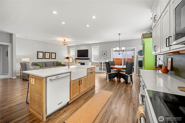 kitchen featuring a notable chandelier, open floor plan, dishwasher, and a sink
