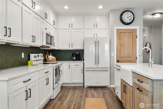 kitchen featuring a sink, white cabinets, white appliances, and dark wood-style floors