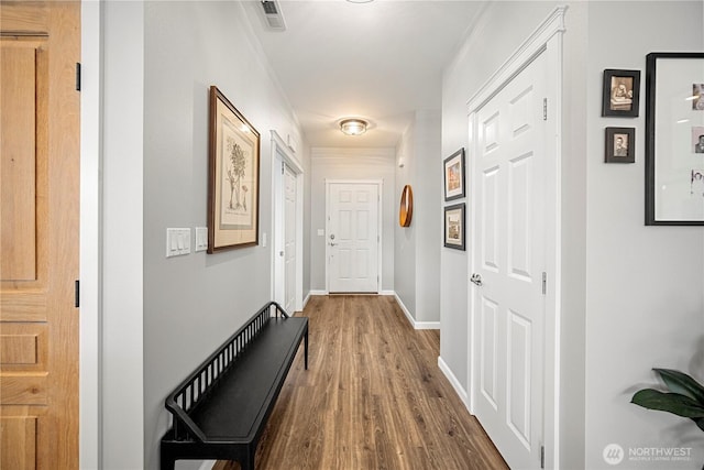 hallway featuring wood finished floors, baseboards, and visible vents