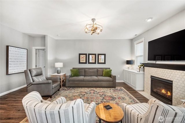 living area with dark wood-style flooring, baseboards, a chandelier, and a fireplace