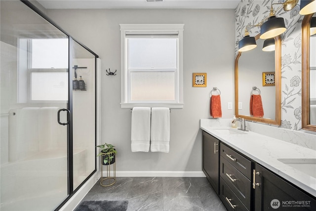 full bath featuring baseboards, double vanity, a shower stall, marble finish floor, and a sink