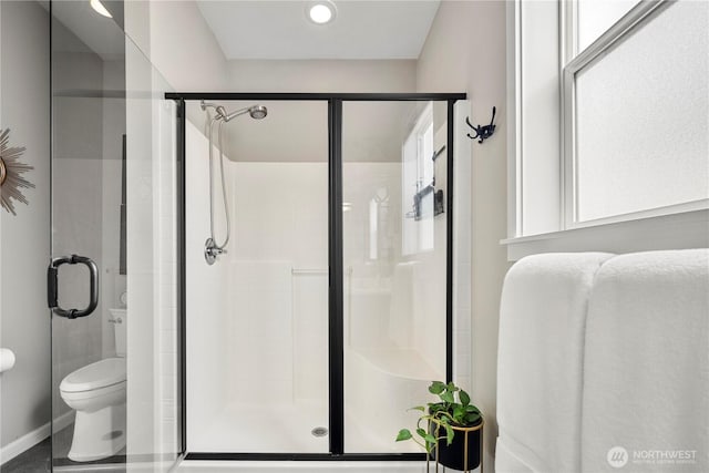 full bathroom featuring toilet, a shower stall, and baseboards