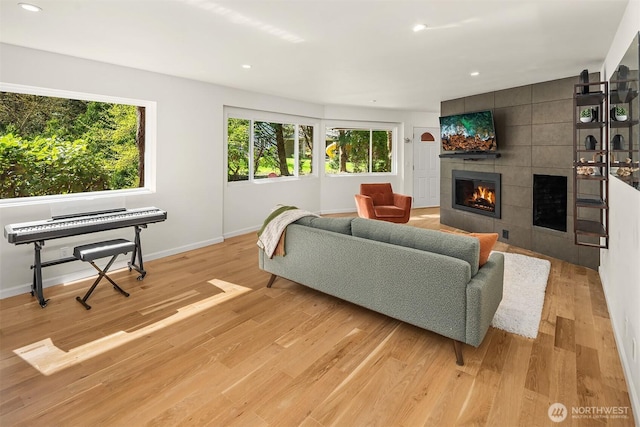living room with light wood-type flooring, a tile fireplace, baseboards, and recessed lighting
