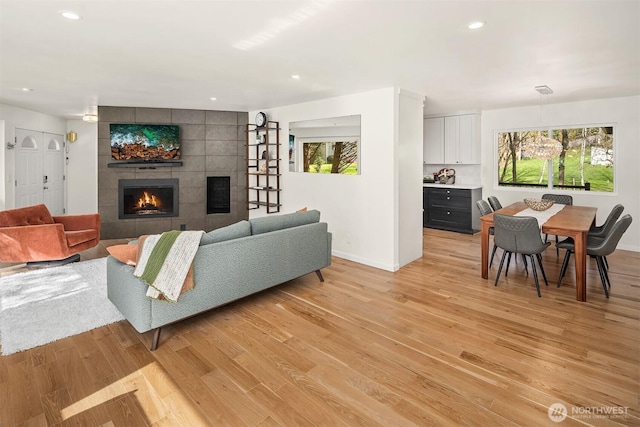 living area featuring a healthy amount of sunlight, light wood-type flooring, recessed lighting, and a fireplace