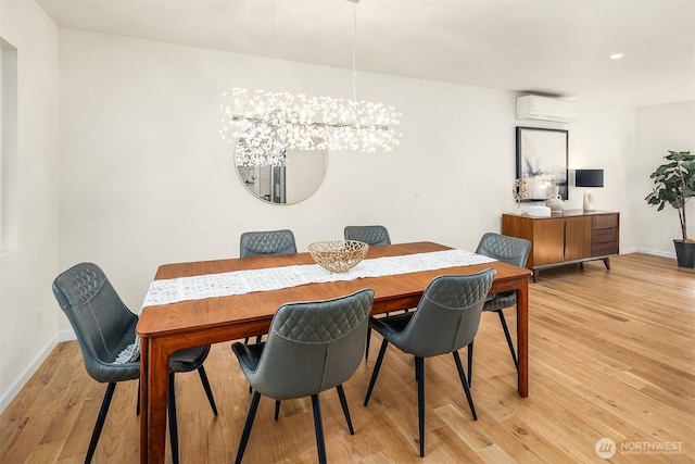 dining room featuring an AC wall unit, baseboards, a notable chandelier, and light wood-style floors