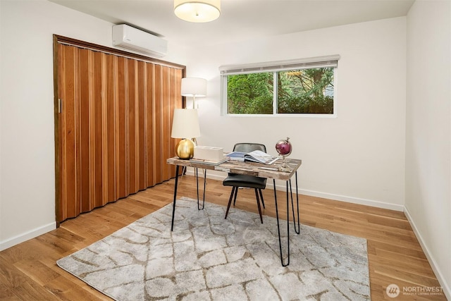 office space featuring wood finished floors, baseboards, and an AC wall unit