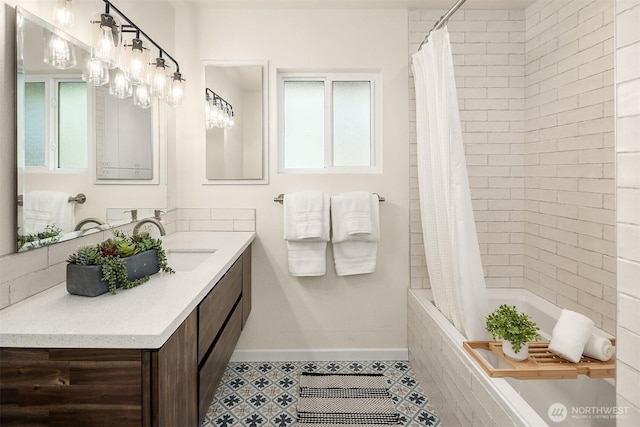bathroom featuring vanity, baseboards, and tiled shower / bath combo