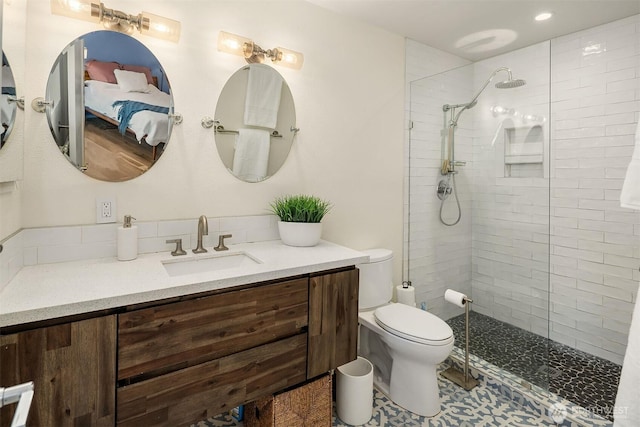 full bath with vanity, a tile shower, and toilet
