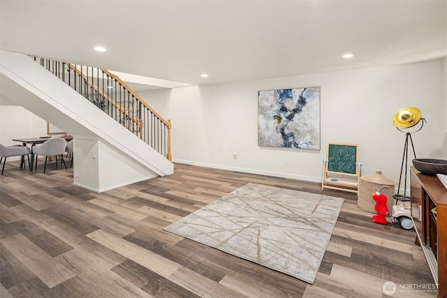 living area with wood finished floors, recessed lighting, and stairway