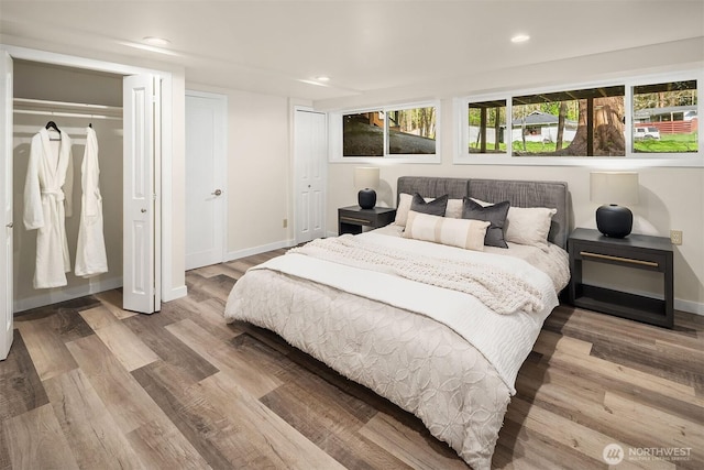 bedroom featuring multiple closets, recessed lighting, wood finished floors, and baseboards
