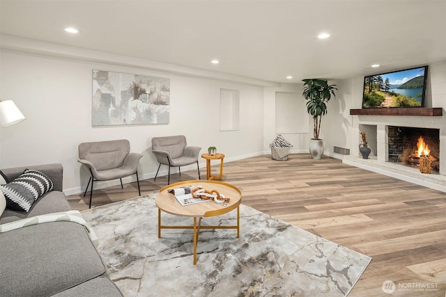 living area with visible vents, recessed lighting, wood finished floors, a brick fireplace, and baseboards