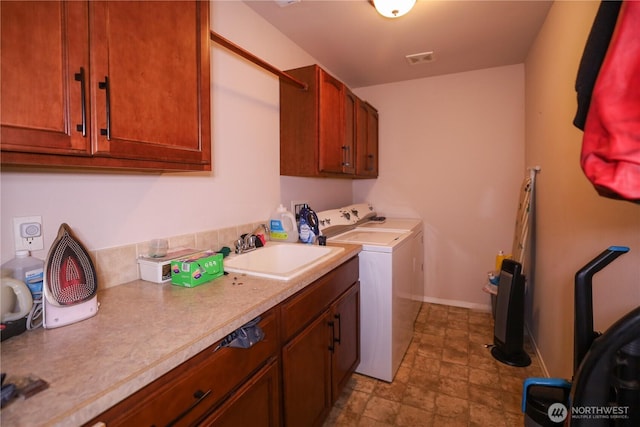 204 Brant Ln, Hoquiam, WA 98550 - laundry area with stone finish floor, baseboards, washing machine and clothes dryer, a sink, and cabinet space