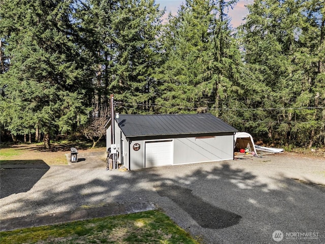 14205 205th Street Ct E, Graham, WA 98338 - detached garage featuring driveway and a view of trees