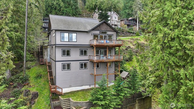 rear view of house featuring stairs and a forest view