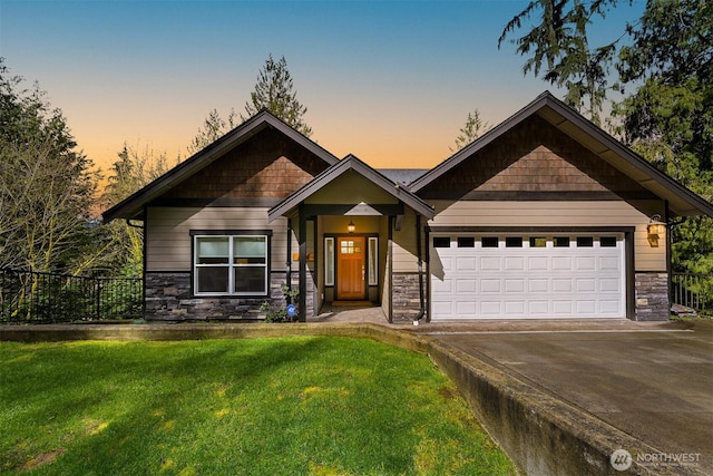 craftsman-style house featuring a yard, an attached garage, stone siding, fence, and driveway