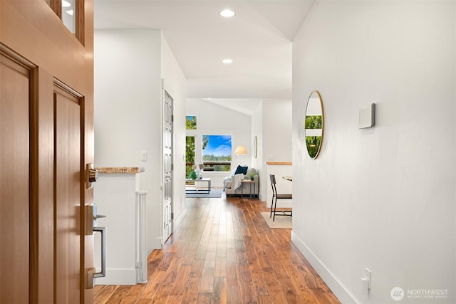 hall with recessed lighting, vaulted ceiling, light wood-type flooring, and baseboards