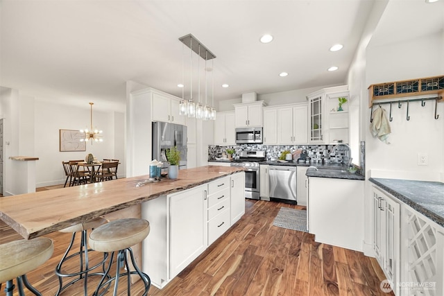 kitchen featuring dark wood-style flooring, a center island, backsplash, white cabinetry, and appliances with stainless steel finishes