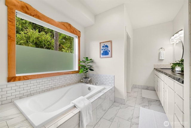 full bathroom featuring a bath, marble finish floor, vanity, and baseboards