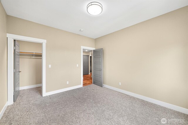 unfurnished bedroom featuring a closet, baseboards, a spacious closet, and carpet