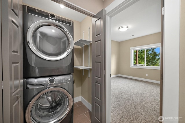 washroom with carpet, stacked washer / dryer, laundry area, and baseboards