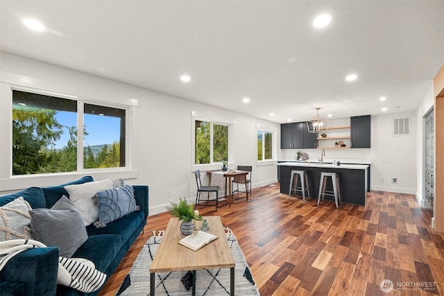 living room with recessed lighting, visible vents, baseboards, and wood finished floors