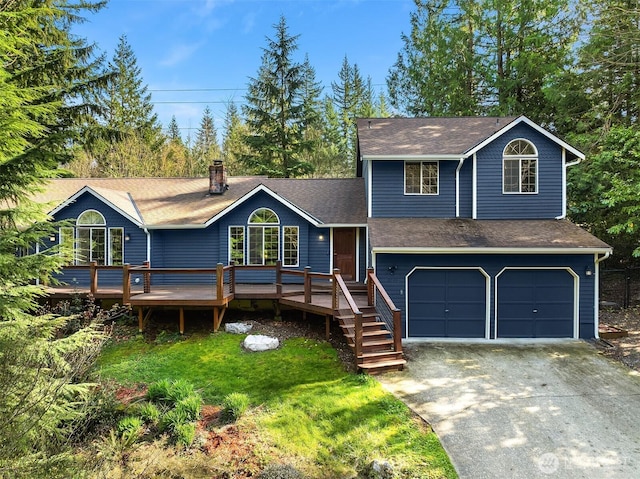 tri-level home with an attached garage, a chimney, a front lawn, driveway, and roof with shingles