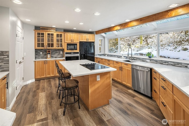 kitchen featuring a sink, a breakfast bar, dark wood finished floors, beamed ceiling, and black appliances