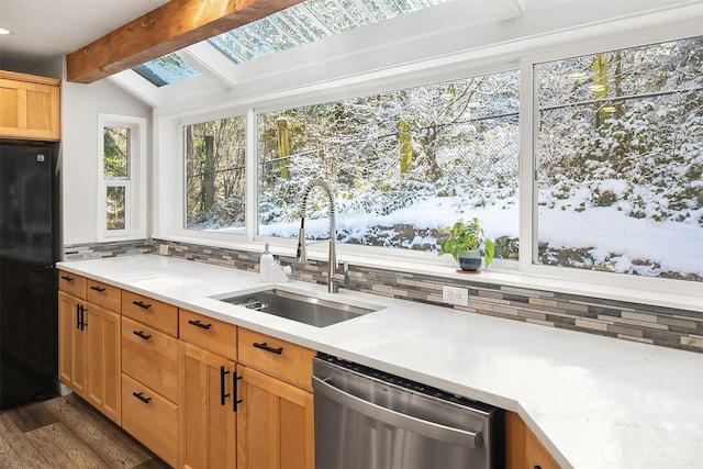 kitchen featuring light countertops, freestanding refrigerator, backsplash, dishwasher, and a sink