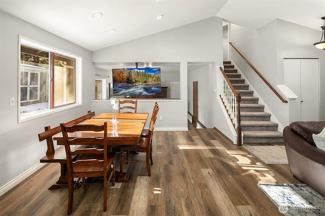 dining area with wood finished floors, baseboards, lofted ceiling, and stairway