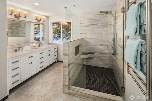 full bath featuring double vanity, a sink, and a stall shower