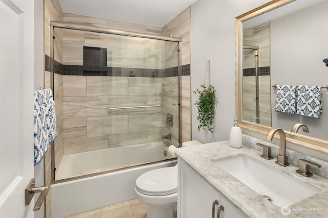 bathroom featuring tile patterned flooring, toilet, vanity, and bath / shower combo with glass door