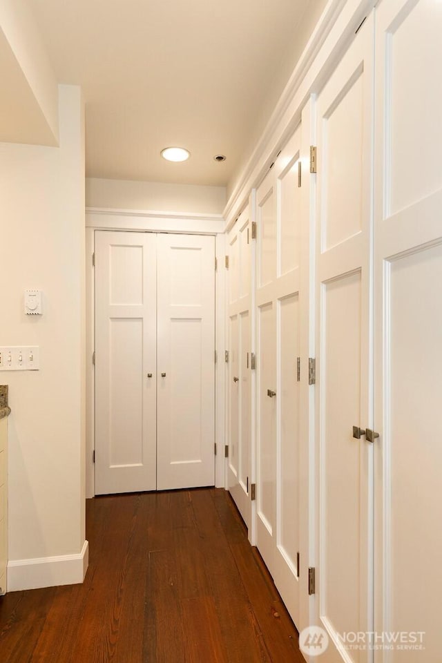 hall featuring dark wood finished floors, baseboards, and recessed lighting