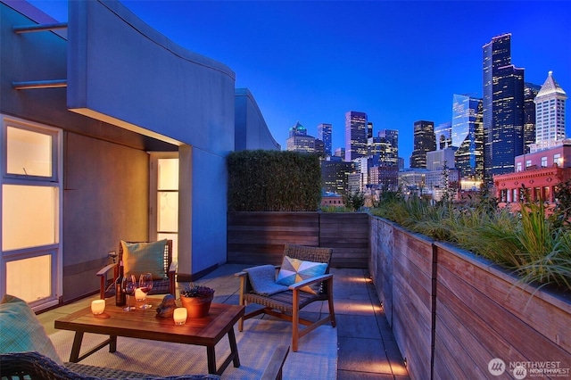 balcony at twilight featuring a view of city lights and a patio area