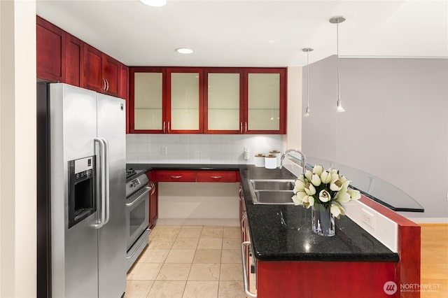kitchen featuring tasteful backsplash, a peninsula, appliances with stainless steel finishes, a sink, and reddish brown cabinets