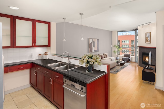 kitchen featuring open floor plan, a peninsula, backsplash, dark countertops, and a sink