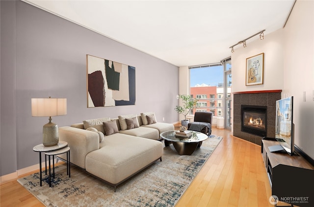 living room featuring expansive windows, a tile fireplace, baseboards, track lighting, and wood-type flooring