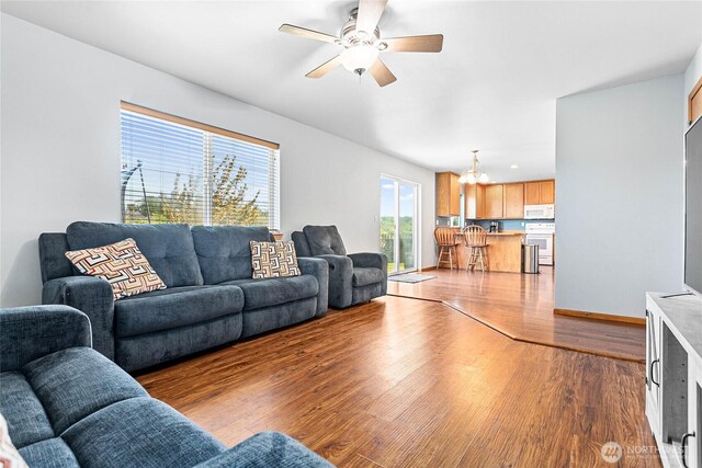 living room with wood finished floors, a ceiling fan, and baseboards