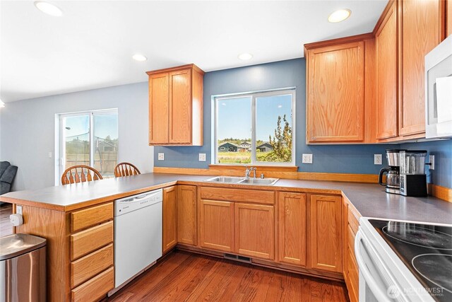 kitchen featuring white appliances, a peninsula, plenty of natural light, a sink, and recessed lighting