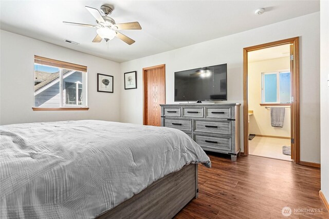bedroom with dark wood-type flooring, baseboards, a ceiling fan, and connected bathroom