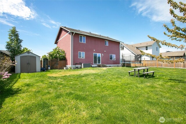 back of property with a storage shed, a trampoline, entry steps, and an outbuilding
